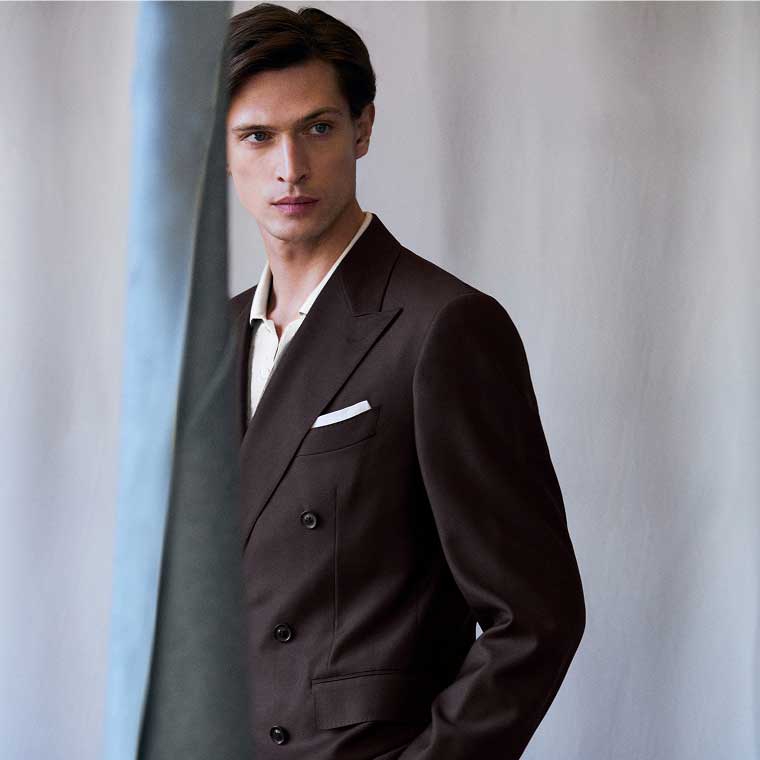 A male model wearing a suit with the jacket unbuttoned.