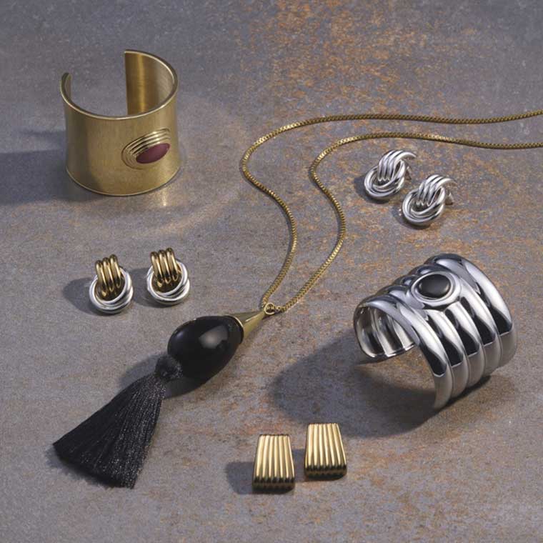A grouping of silver and gold jewellery on a grey backdrop.