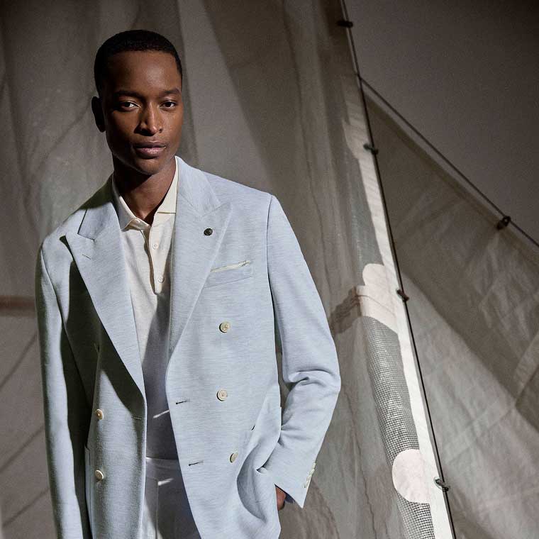 A model wearing a light blue suit over a white shirt.