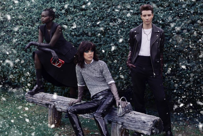 Three models in different monochromatic outfits posing on a bench in front of a winter backdrop