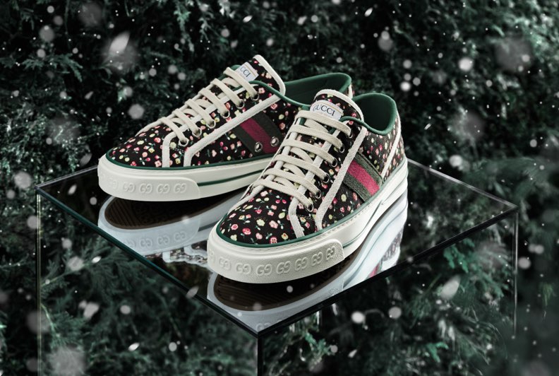 Patterned sneakers photogrpahed on a mirored surface with green foliage in the bakground