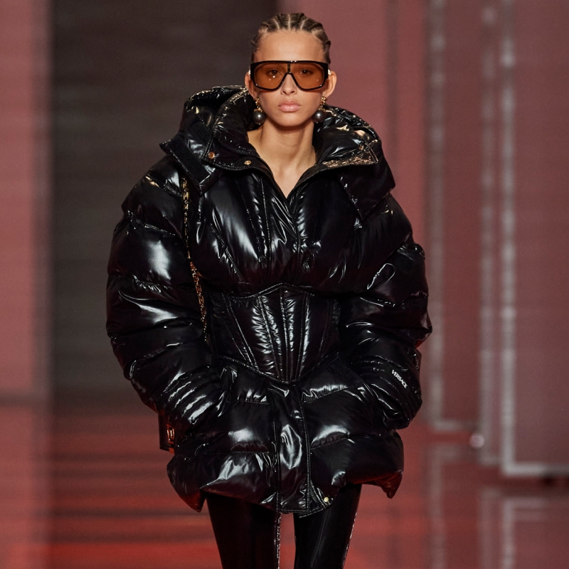 A model wearing a sweater with a graphic print and a plaid skirt.