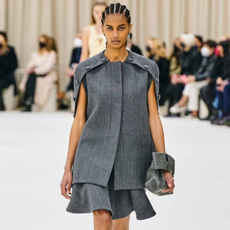 A model wearing a grey vest with cap sleeves and a trumpet skirt.