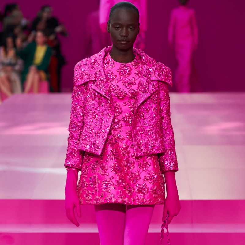 A model wearing an embellished hot pink jacket over a matching mini dress.