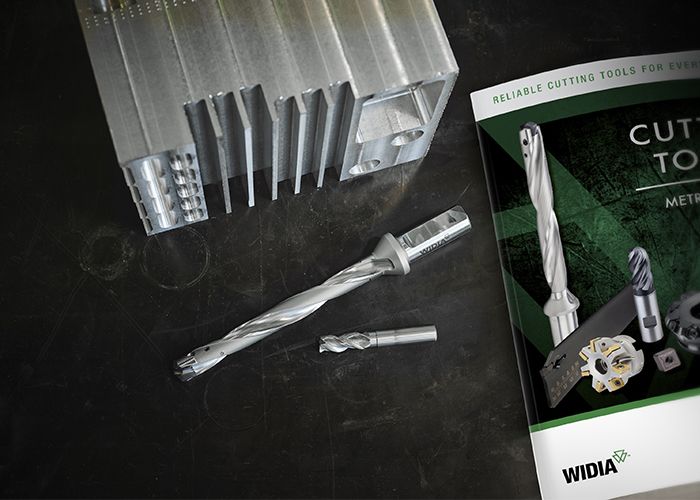 Machined metal, WIDIA modular drill, WIDIA solid end mill, and 2022 Cutting Tool Catalog on a table