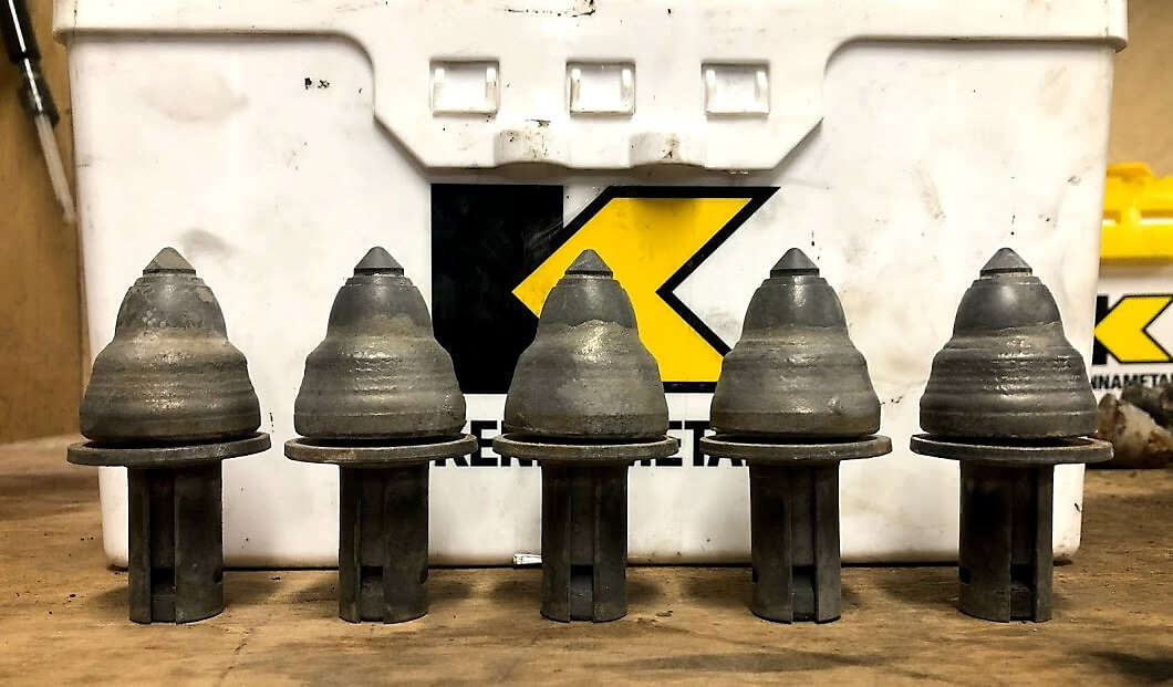 Five Road King PCD teeth lined up against a Kennametal box