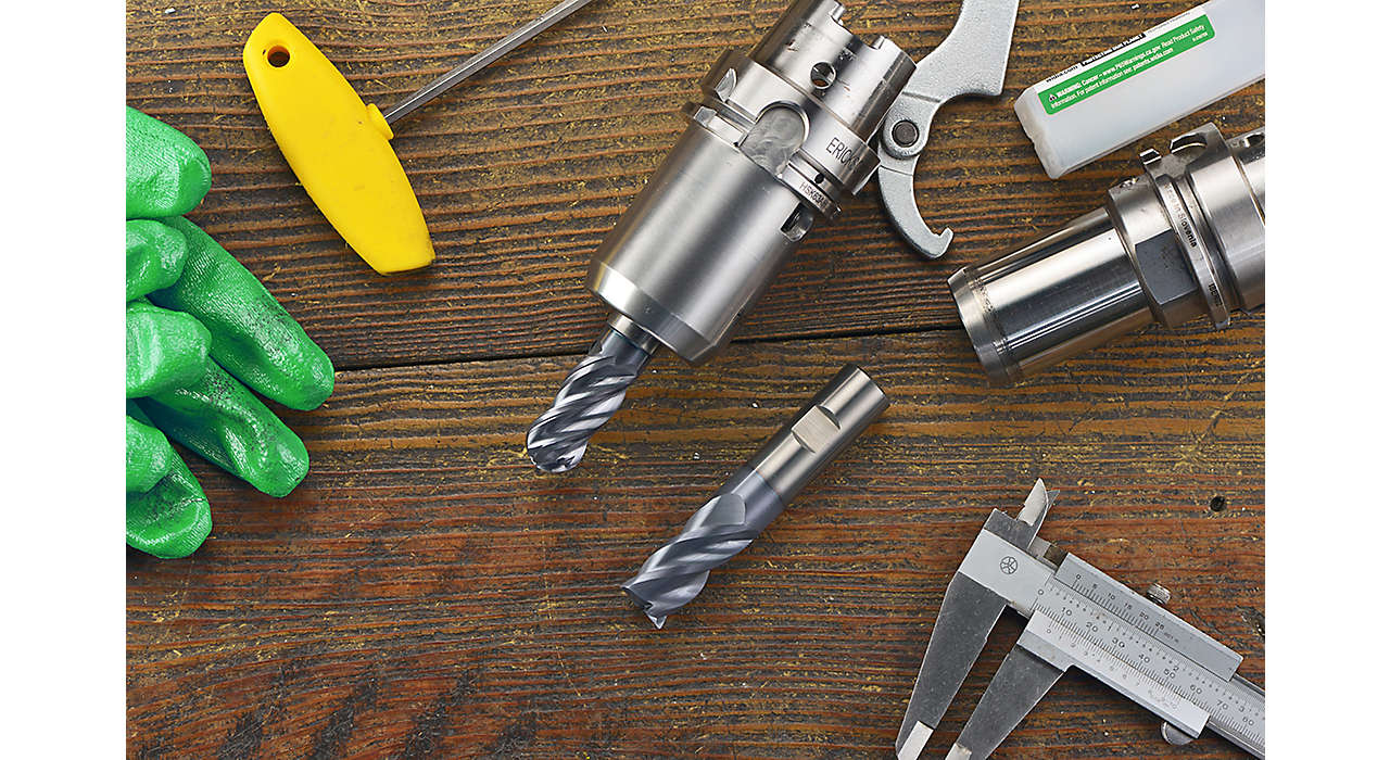 WIDIA WCE4 and WCE4 ball-nose solid end mills on a wood table surrounded by green gloves, milling tool holders, and other tools