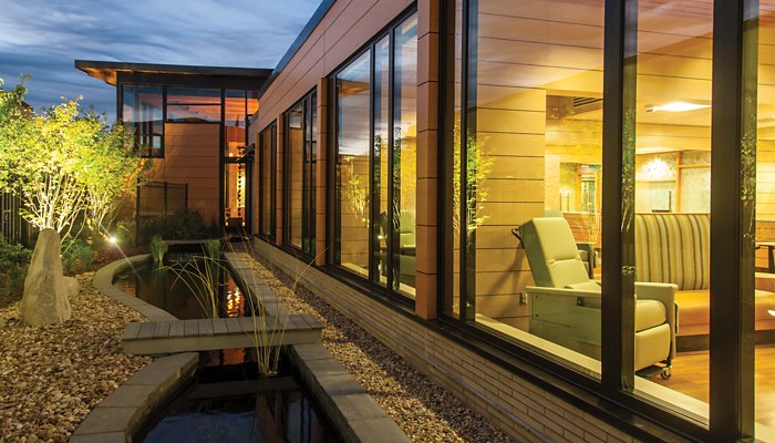 Exterior night view of a healthcare facility with a reclining Champion Chair seen through a window