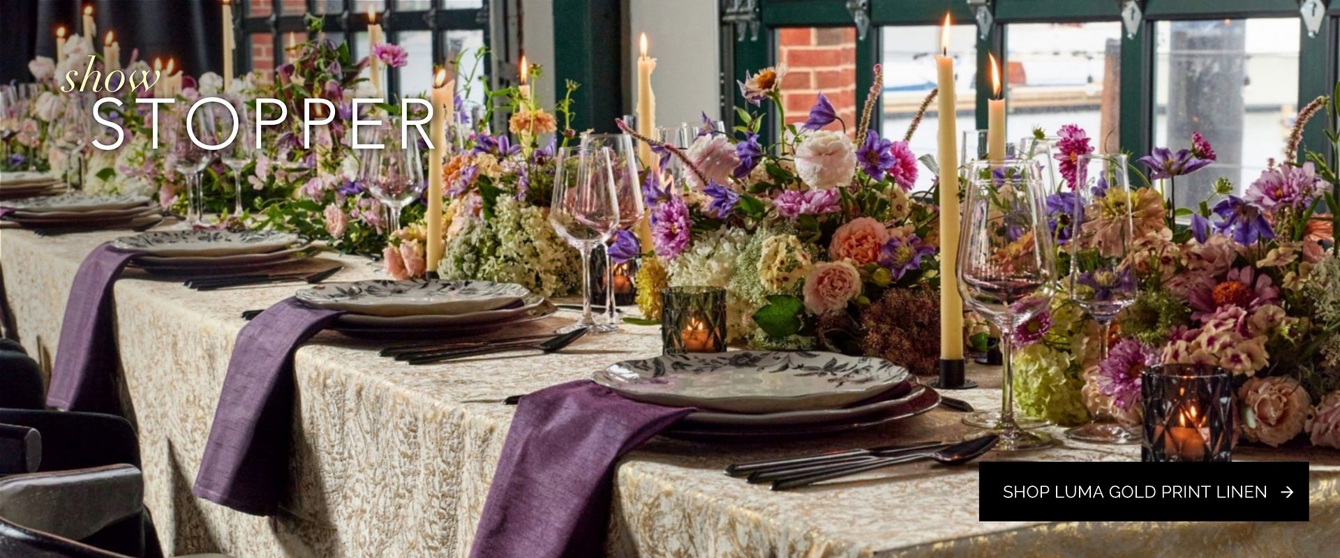 Gold holiday linen tabletop setting with plum napkins and lush purple, pink and plum florals
