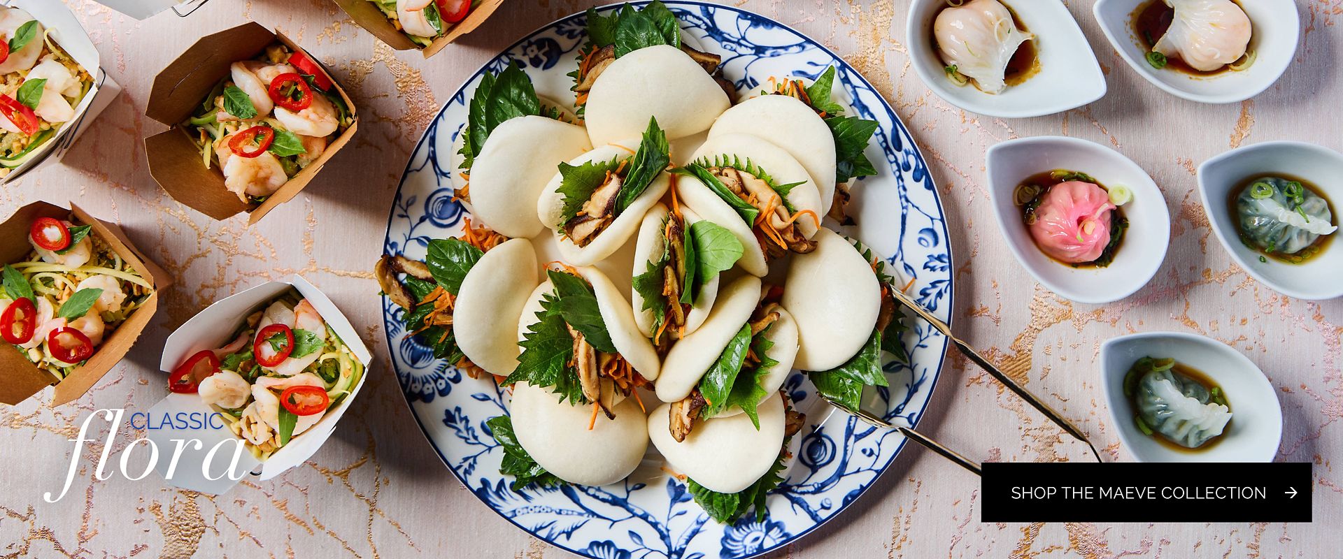 Blue and white floral Maeve Collection plate featuring a spread of bao buns and small tasting bowls