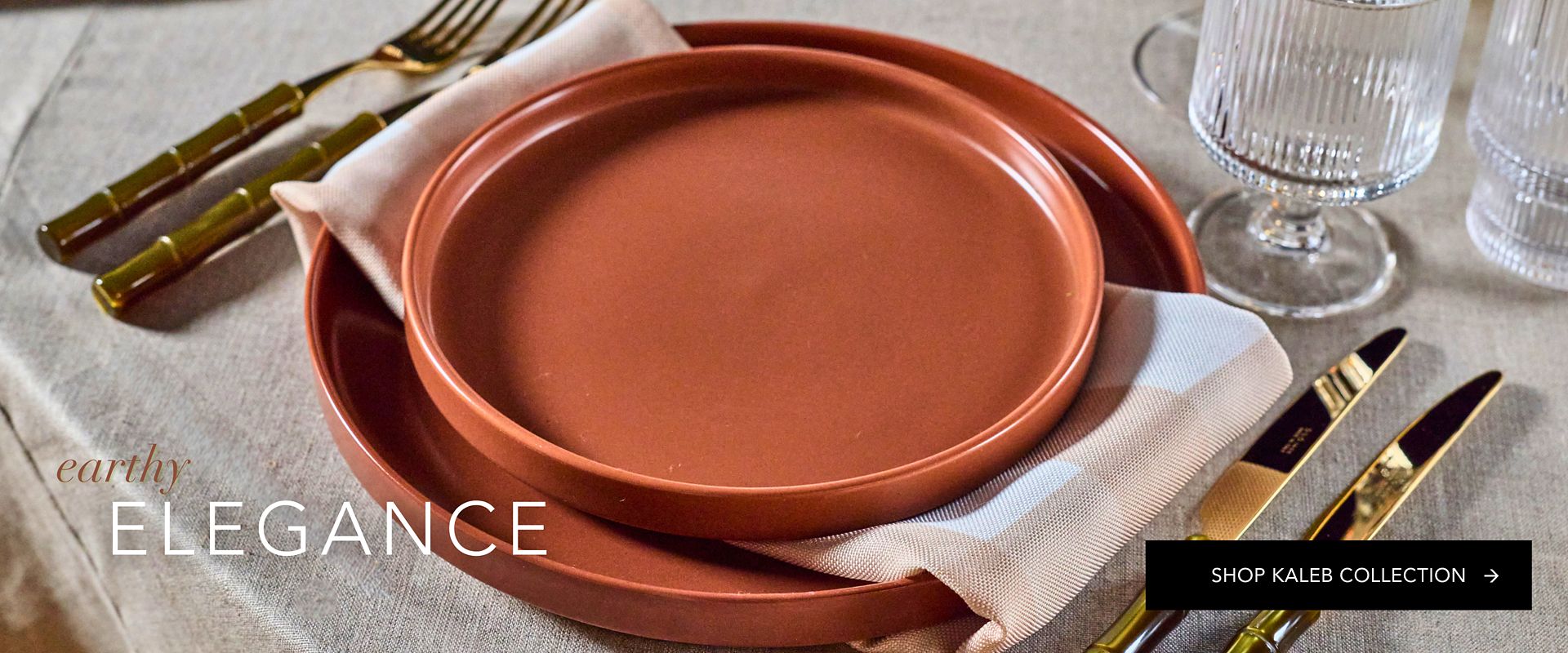 Kaleb Collection terracotta plates featuring a matte, artisanal pottery finish, styled with gold bamboo flatware and ribbed glassware.
