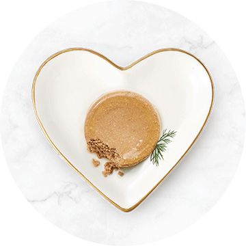 white heart shaped bowl with a gold rim filled with cat food loaf and dill garnish