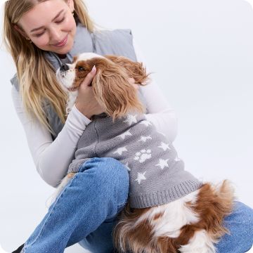 Woman playing with dog in sweater