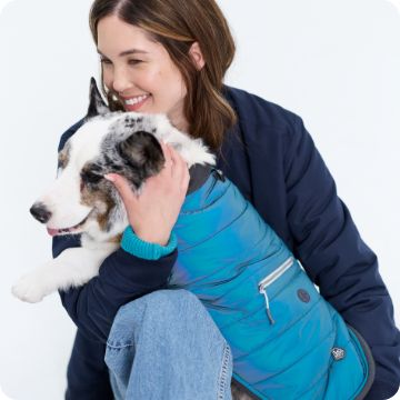 Woman hugging dog in warm vest