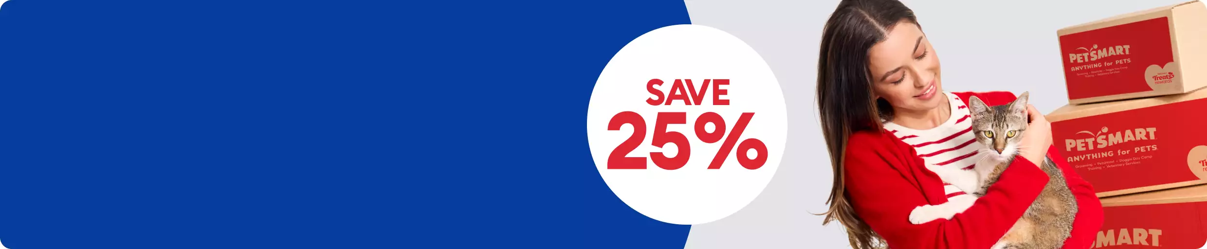Woman in red sweater holding a gray cat beside stacked PetSmart shipping boxes with a Save 25% callout