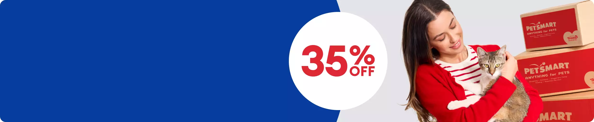 Woman in red sweater holding a gray cat beside stacked PetSmart shipping boxes with a 35% OFF callout