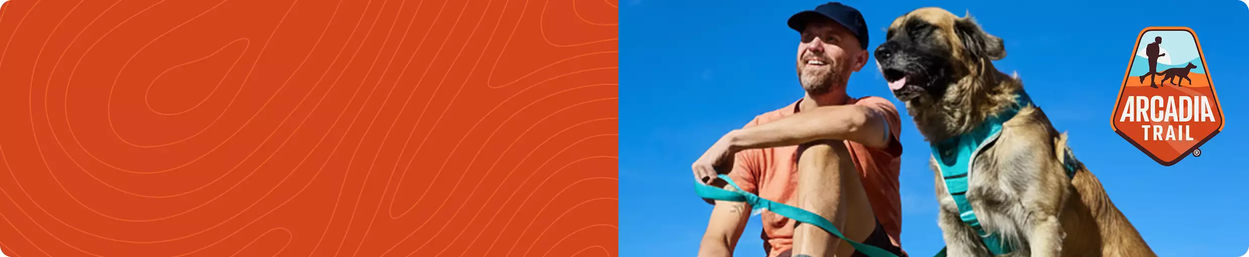 Man sitting outdoors with a large dog wearing a teal harness & an Arcadia Trail logo