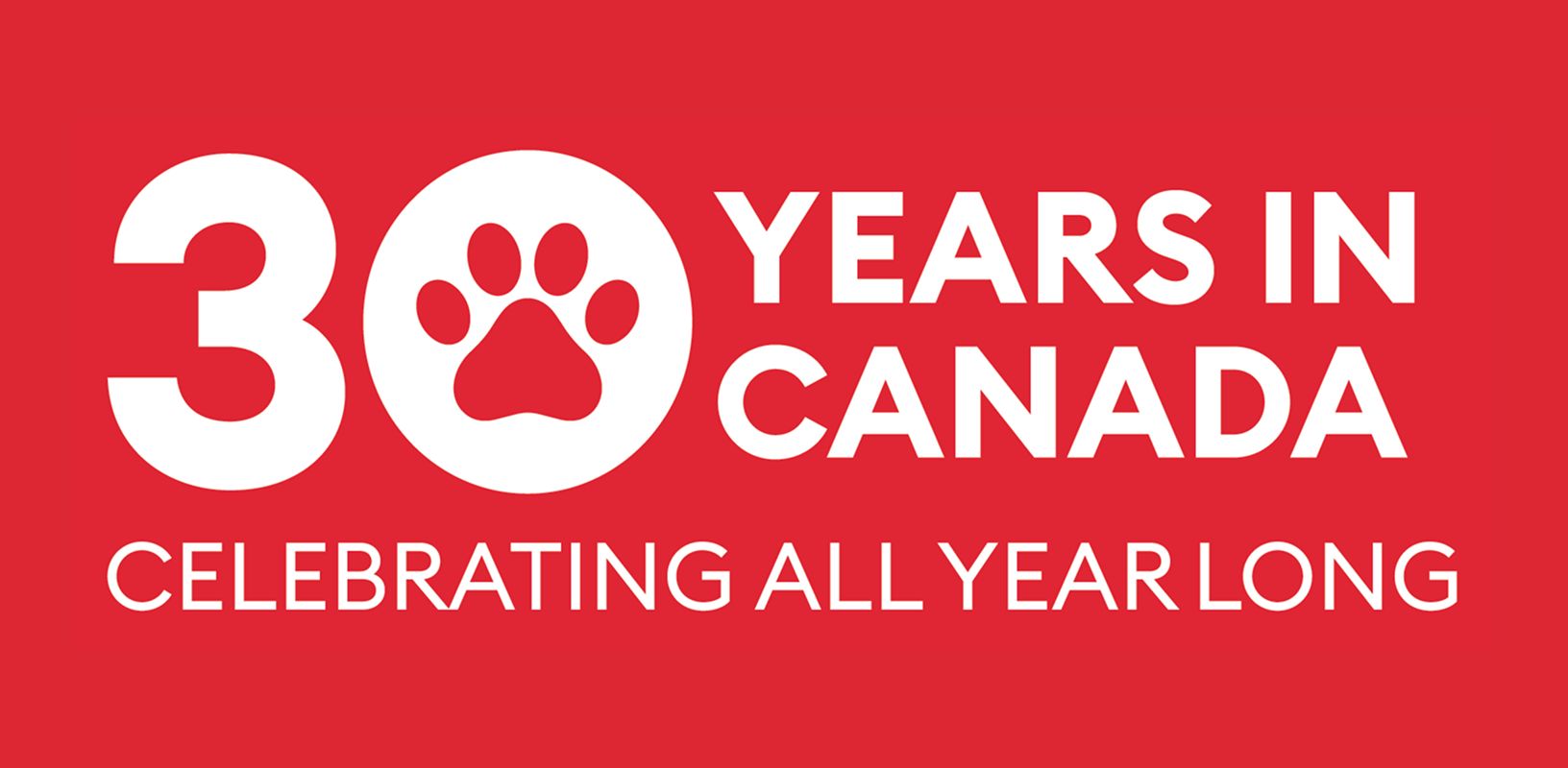 Shaggy dog & a cat lying together beside a PetSmart 30th Anniversary badge with red, white & blue accents