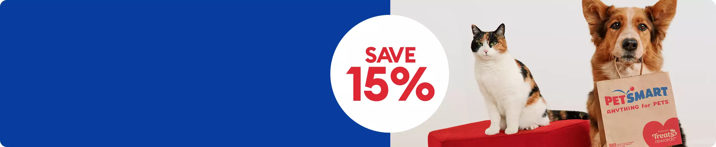 Dog holding a PetSmart shopping bag next to a cat on a red stool & a save 15% callout