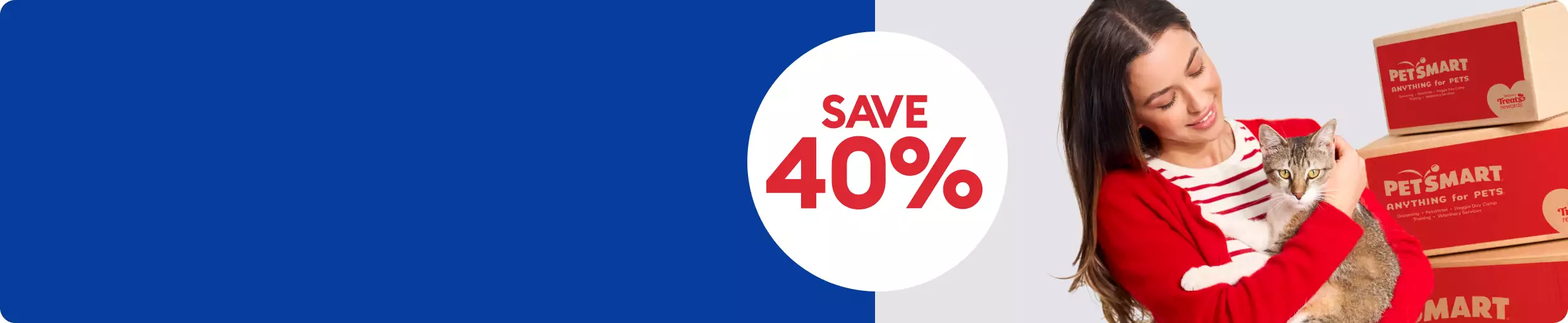 Woman in a red sweater holding a cat next to PetSmart boxes & a save 40% callout