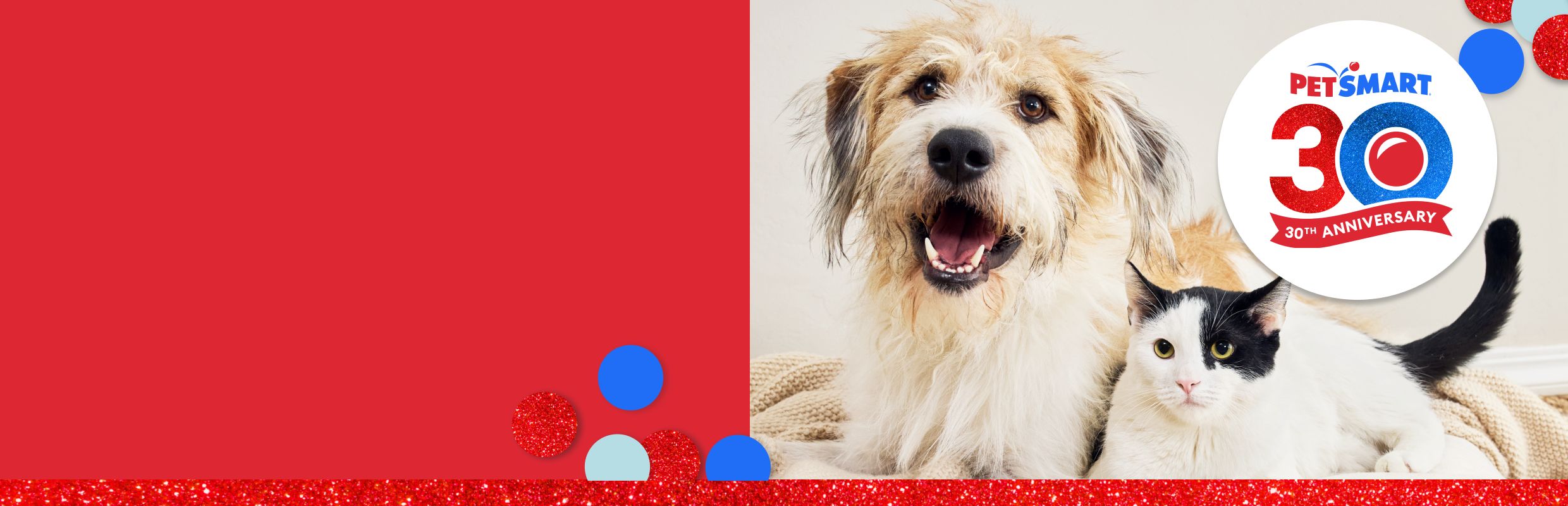 Dog and black-and-white cat lying together and a PetSmart 30th anniversary logo with red, white & blue confetti accents