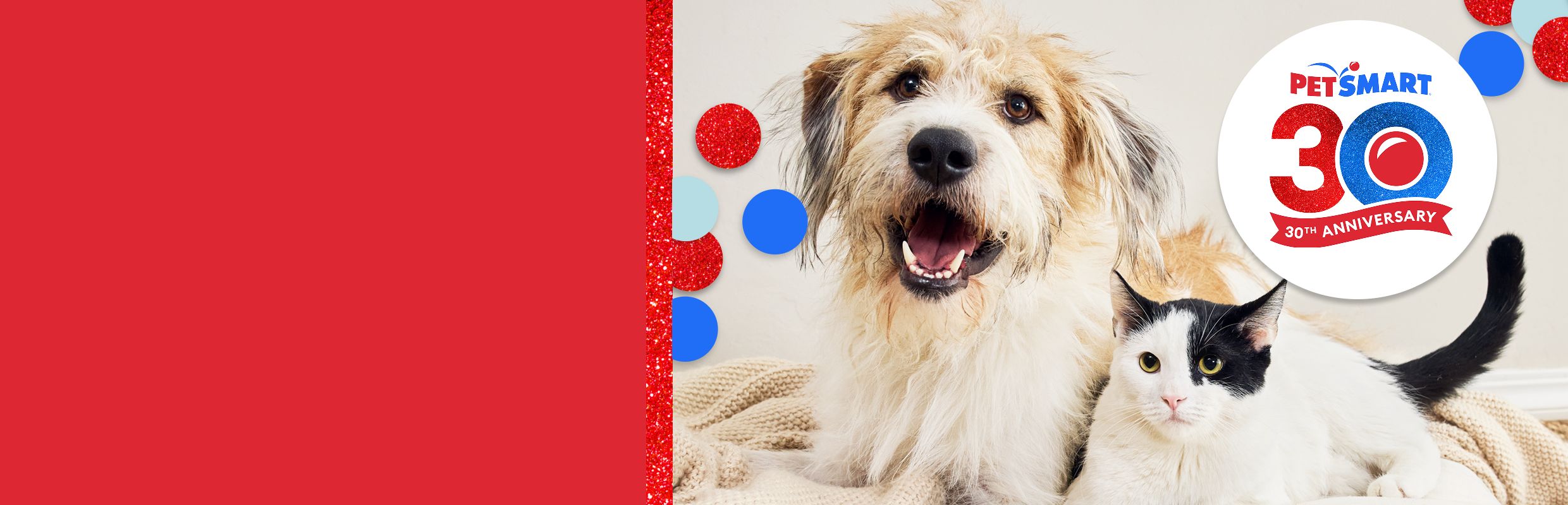 Dog and black-and-white cat lying together and a PetSmart 30th anniversary logo with red, white & blue confetti accents