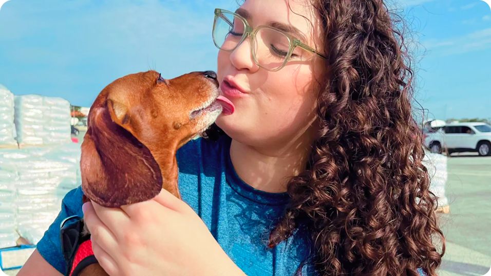 Woman holding a dog who's licking her face