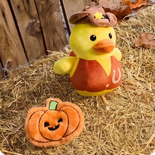 Plush cowboy duck & pumpkin toy on top of hay