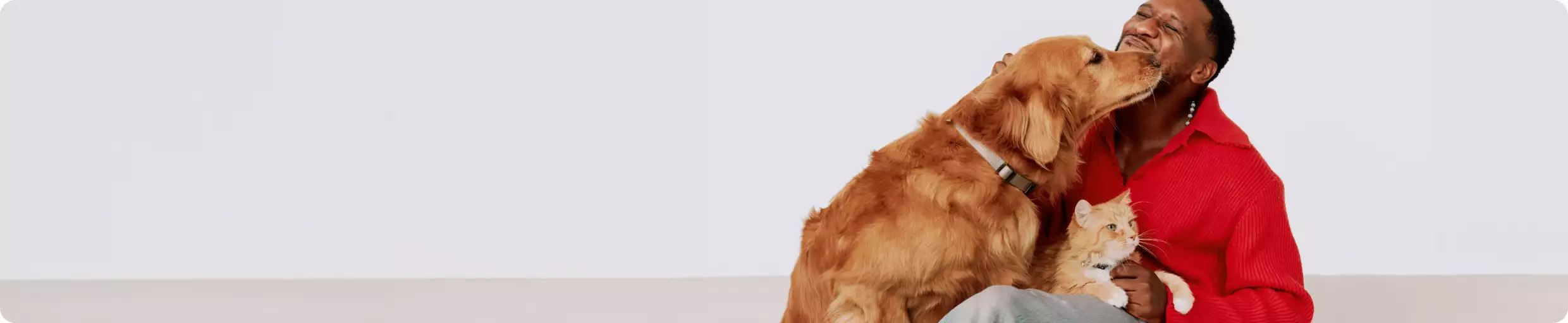 A man sitting and petting a dog & a cat