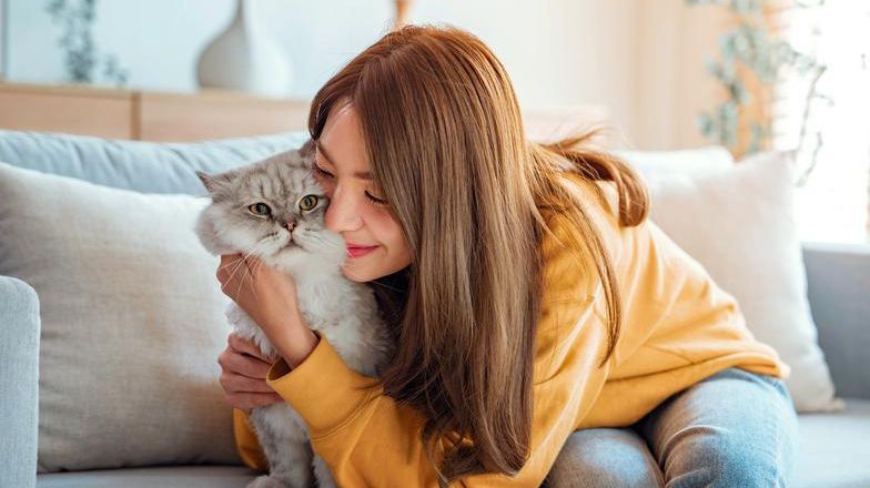 Woman hugging a cat on a couch