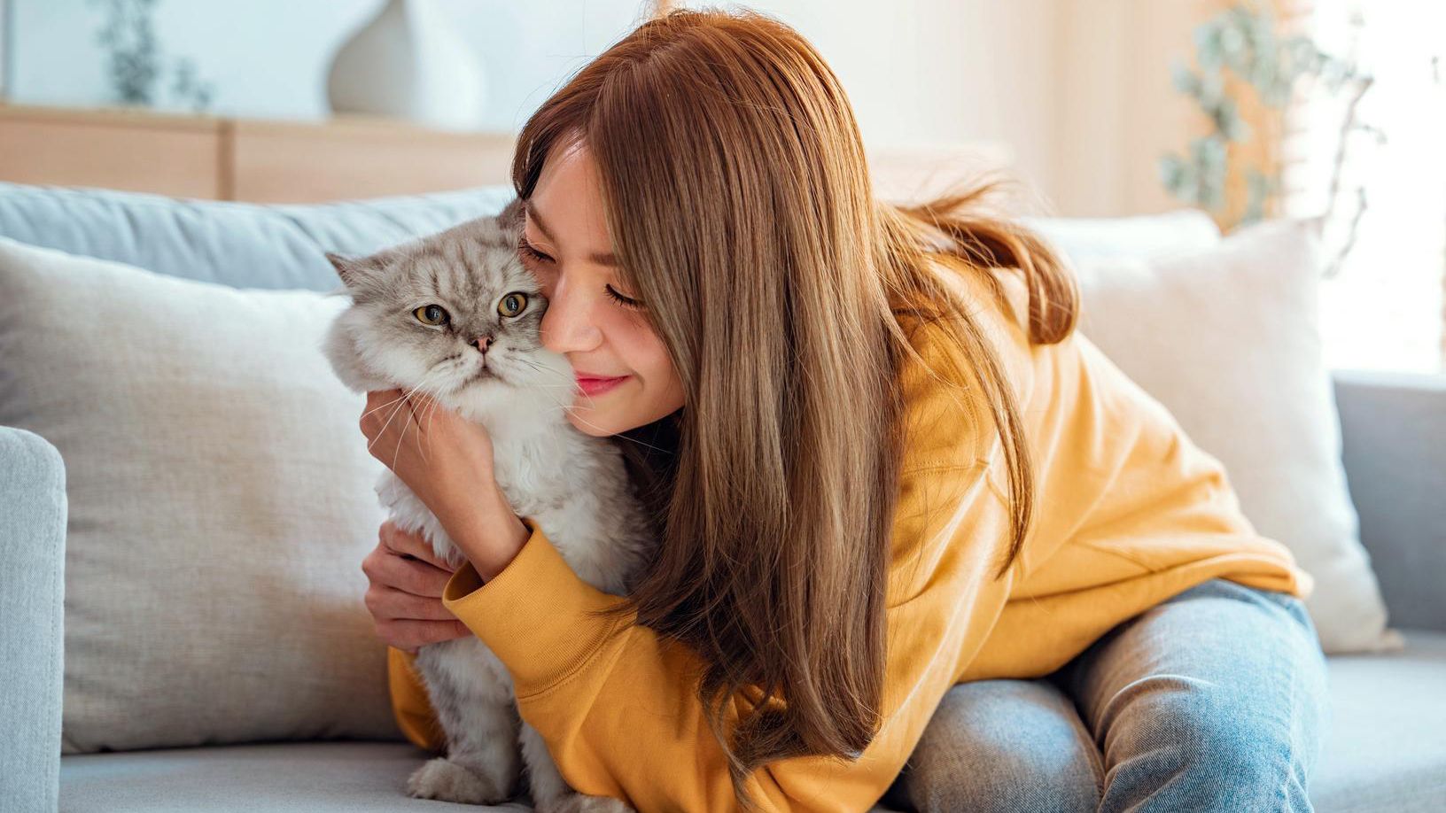 Woman hugging a cat on a couch