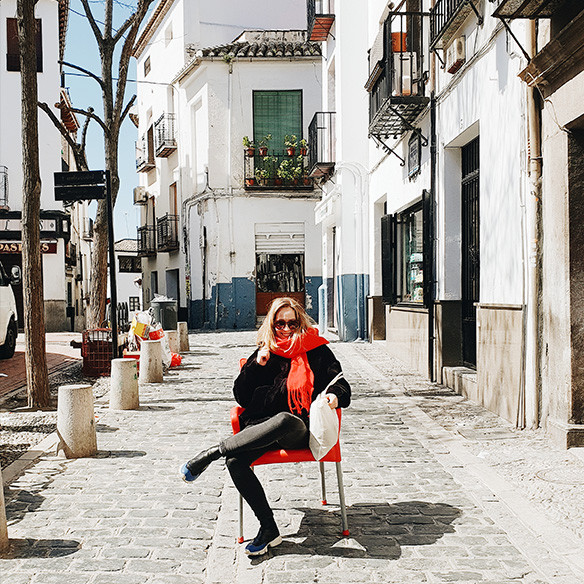 A photo captured with Galaxy by Instagram user @inescostamonteiro of a woman sitting on a red chair in the middle of a sidewalk