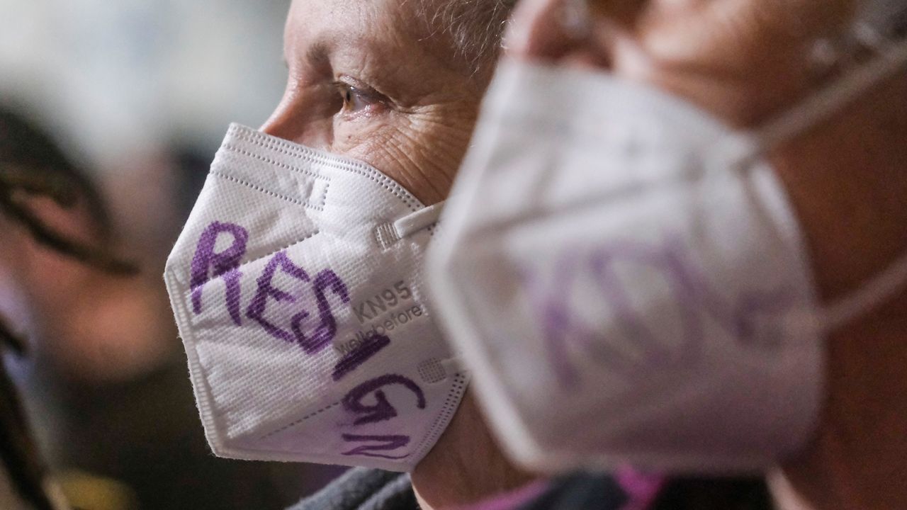 Protesters wearing face mask during the Los Angeles City Council meeting Tuesday, Dec. 13, 2022 in Los Angeles. A small group of protesters is chanting throughout the meeting calling for the resignations of Councilman Kevin de Leon. (AP Photo/Ringo H.W. Chiu)