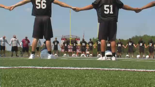 St. Michael's High School football team holding hands during practice. (Spectrum News)