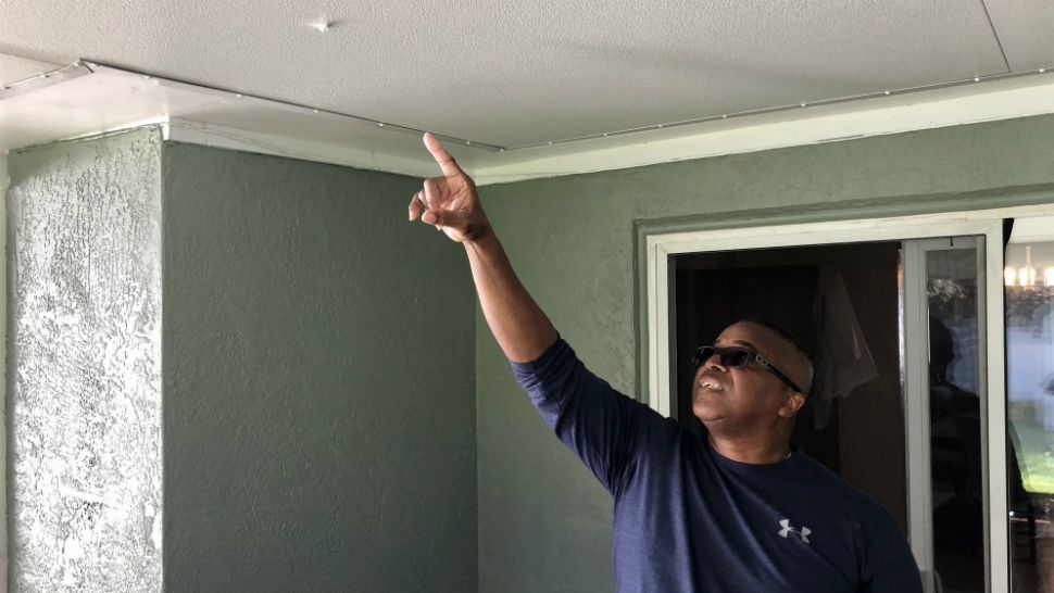Retired St. Petersburg Police Officer Les Harris points to the hole in his patio roof caused by New Year's Eve celebratory gunfire. (Josh Rojas/Spectrum Bay News 9)