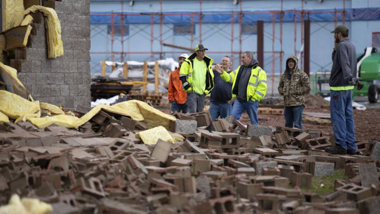 Stewart Richey Electrical employees and other utility workers and city crews survey and help clear debris at Thornton Furniture on Cave Mill Road in Bowling Green, Ky., after another tornado warning was issued, Saturday, Jan. 1, 2022, for Warren and surrounding counties, following the devastating tornadoes that tore through town on Dec. 11, 2021. Though the damage from Saturday's storm proved less catastrophic than the system that passed through in December, heavy rain and strong winds battered the area, causing damage along Cave Mill Road and the surrounding area. (AP Photo/Grace Ramey)