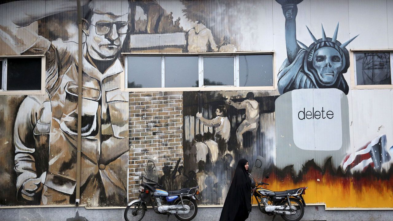 In this file photo from November 2, 2013, an unidentified woman walks under anti-U.S. graffiti painted on the walls of the former U.S. Embassy in Tehran, Iran. (Ebrahim Noroozi/AP)