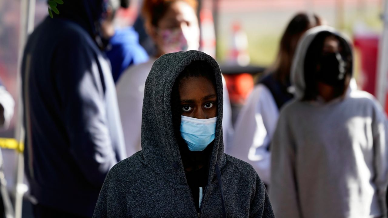 A young person wears a mask while waiting in line at a COVID-19 testing site on the Martin Luther King Jr. medical campus Monday, Jan. 3, 2022, in Los Angeles. (AP Photo/Marcio Jose Sanchez)
