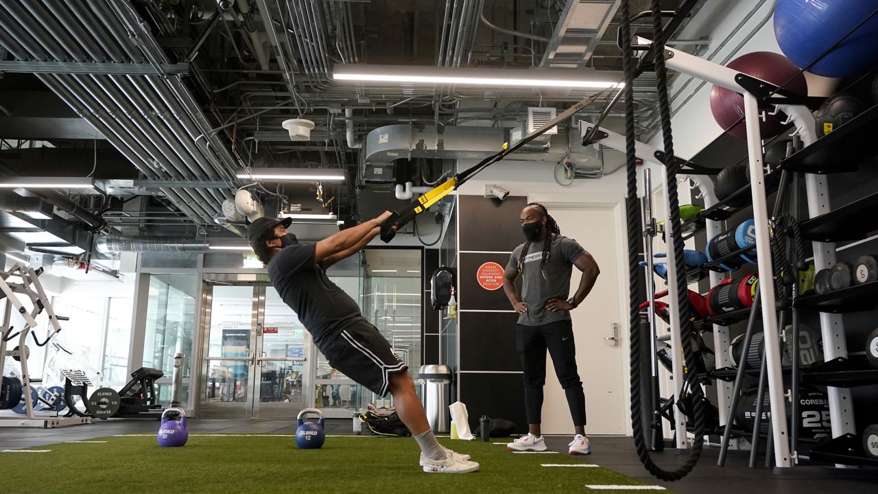 Fitness SF Transbay trainer T. J. Everett, right, watches as Tim Robles works out at the gym during the coronavirus outbreak in San Francisco, Tuesday, Sept. 15, 2020. (AP Photo/Jeff Chiu)