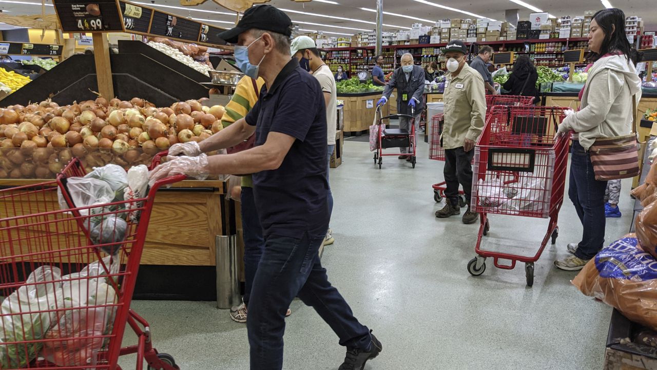 Customers at Super King Markets grocery store wear face masks and gloves April 3, 2020, in Los Angeles. (AP Photo/Damian Dovarganes)