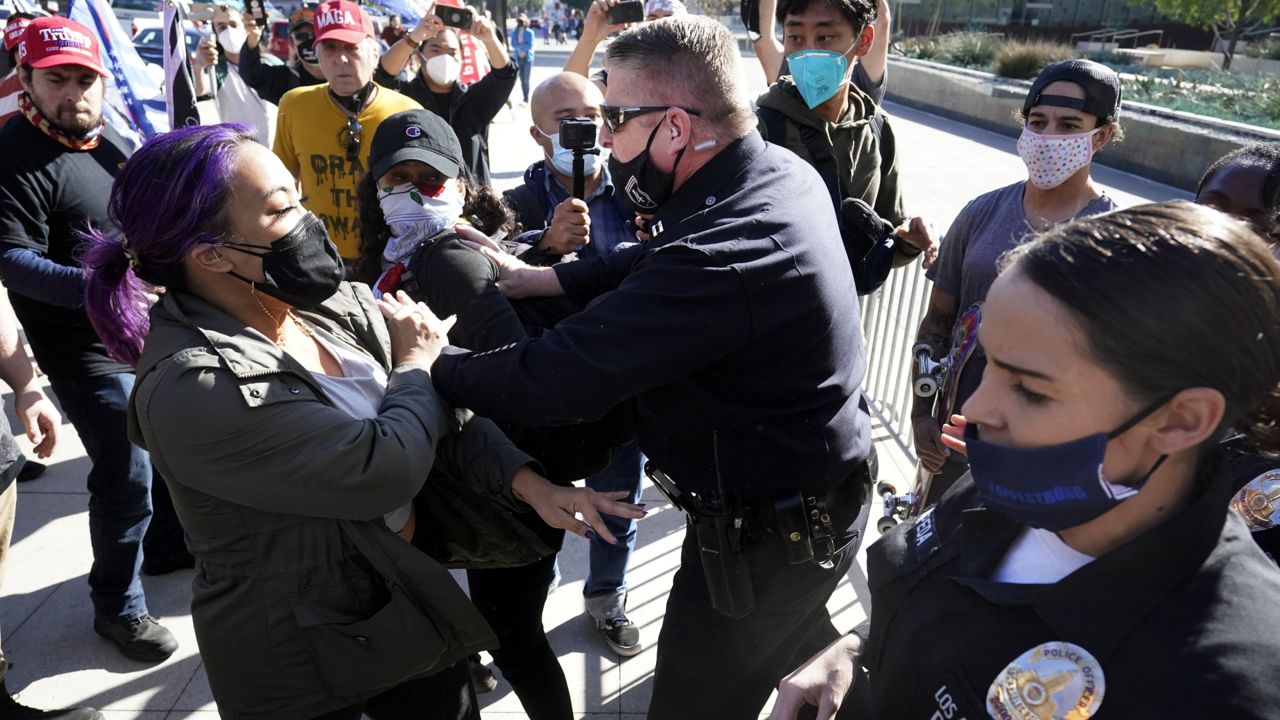 Police shove two counter demonstrators during a pro-Trump rally outside of police headquarters Wednesday, Jan. 6, 2021, in Los Angeles. (AP Photo/Marcio Jose Sanchez)