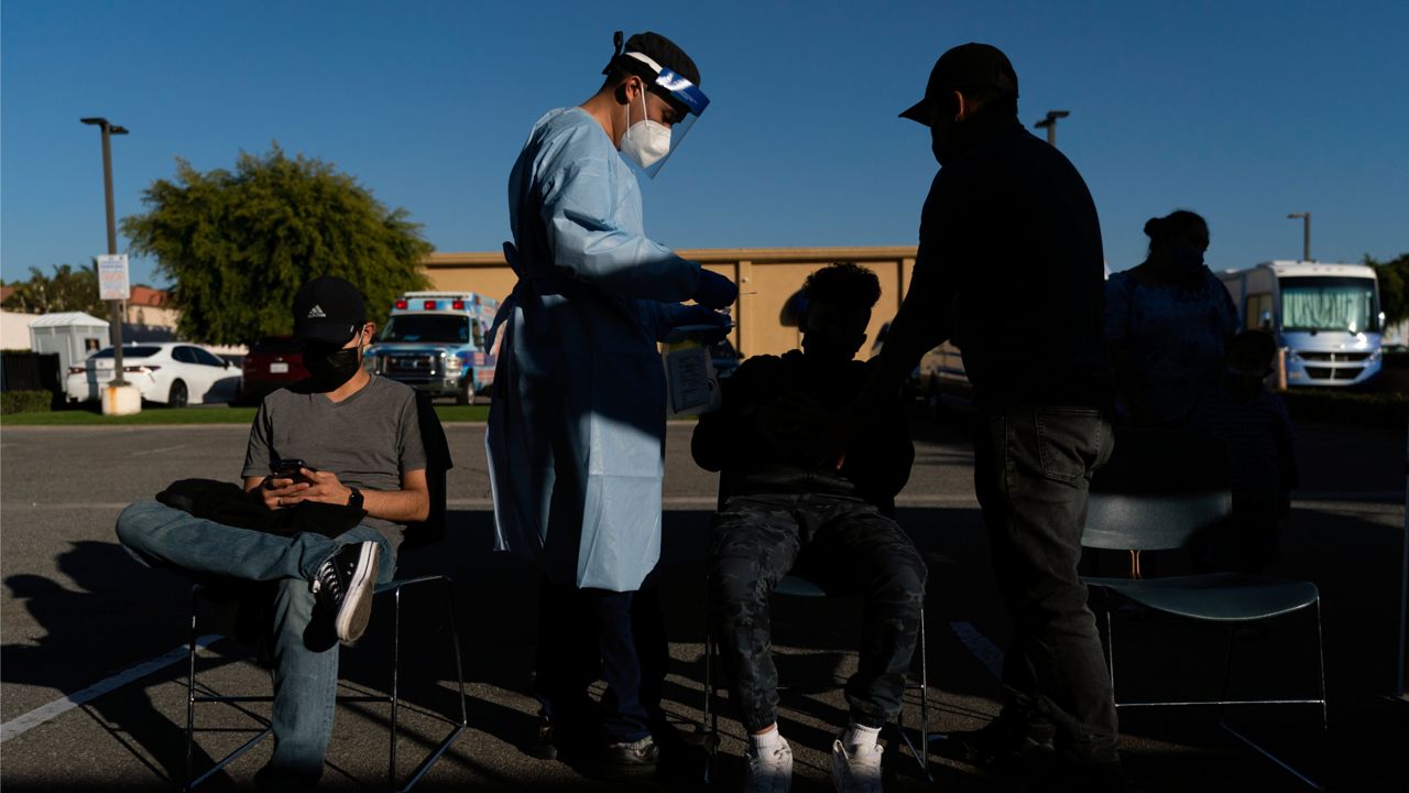 Nurse practitioner Brandon Vinzon collects a nasal swab sample from a boy for a COVID-19 test at Families Together of Orange County community health center in Tustin, Calif., Thursday, Jan. 6, 2022. (AP Photo/Jae C. Hong)