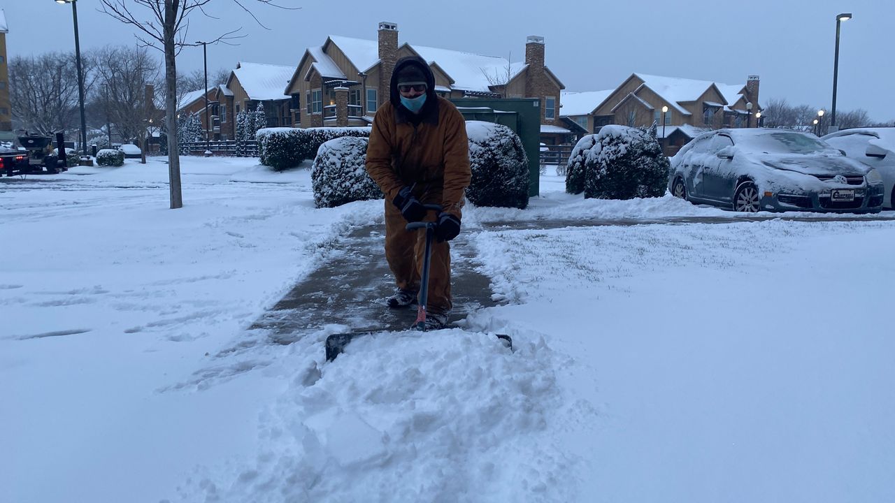 A man shovels snow off a sidewalk. (Spectrum News 1 file photo)