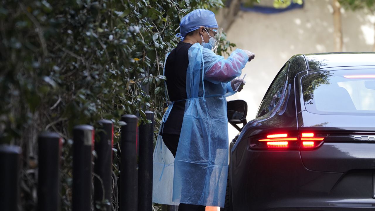 A motorists gets tested inside his Porsche sports car at Good Life Medical Services COVID-19 drive thru site in Los Angeles Thursday, Jan. 7, 2021. (AP Photo/Damian Dovarganes)