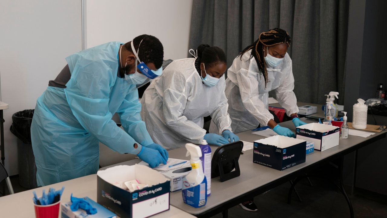 Healthcare workers Henry Paul, from left, Ray Akindele, Wilta Brutus process COVID-19 rapid antigen tests at a testing site in Long Beach, Calif., Thursday, Jan. 6, 2022. (AP Photo/Jae C. Hong)