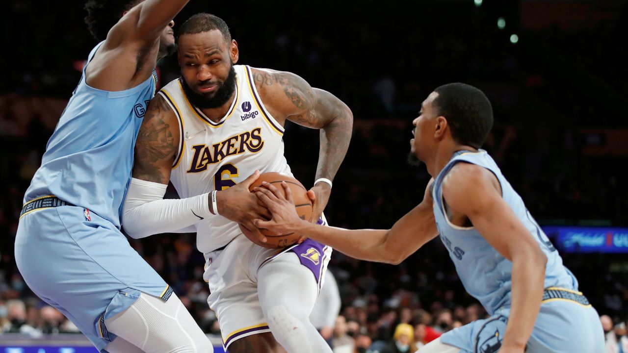 Los Angeles Lakers forward LeBron James, center, collides with Memphis Grizzlies forward Jaren Jackson Jr., left, as guard De'Anthony Melton, right, reaches for the ball during the second half of an NBA basketball game, Sunday, Jan. 9, 2022, in Los Angeles. (AP Photo/Alex Gallardo)
