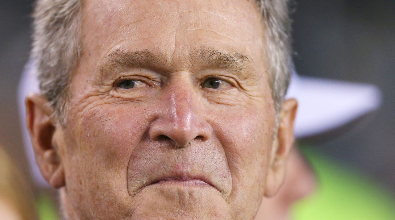 In this Nov. 11, 2018 file photo, President George W. Bush stands on the sidelines before an NFL game in Philadelphia. (AP Photo/Rich Schultz)