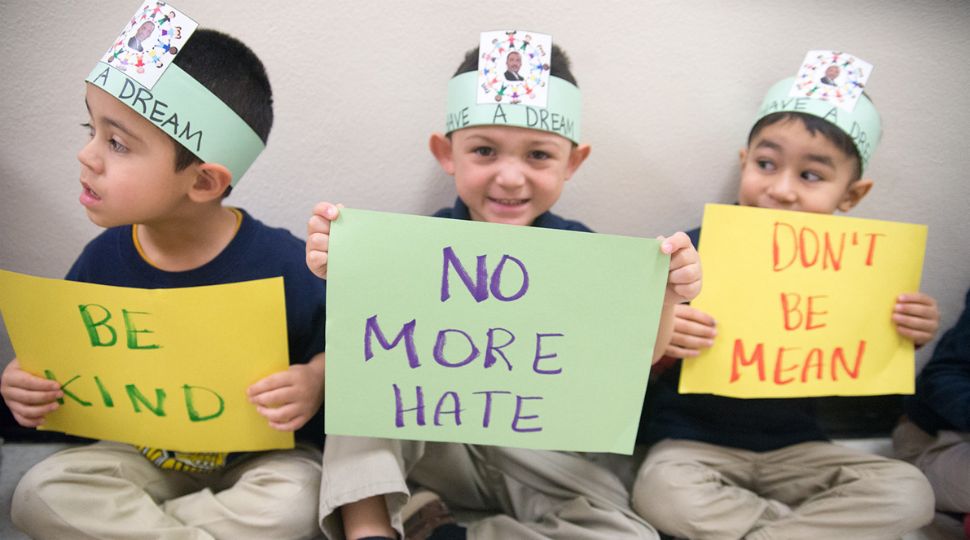 Three young boys sit with signs that read "Be Kind", "No More Hate" and "Don't Be Mean" with paper hats that read "Have a Dream" with an image of Dr. Martin Luther King Jr. on them during an event for San Antonio's annual DreamWeek (Courtesy: DreamWeek San Antonio)