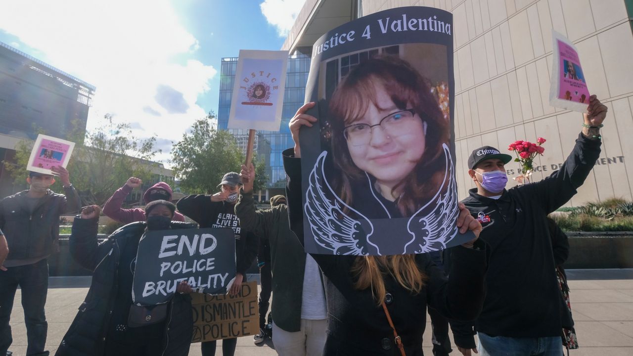 People hold signs with pictures of Valentina Orellana-Peralta during a news conference outside the Los Angeles Police Department headquarters in Los Angeles, Tuesday, Dec. 28, 2021. (AP Photo/Ringo H.W. Chiu)