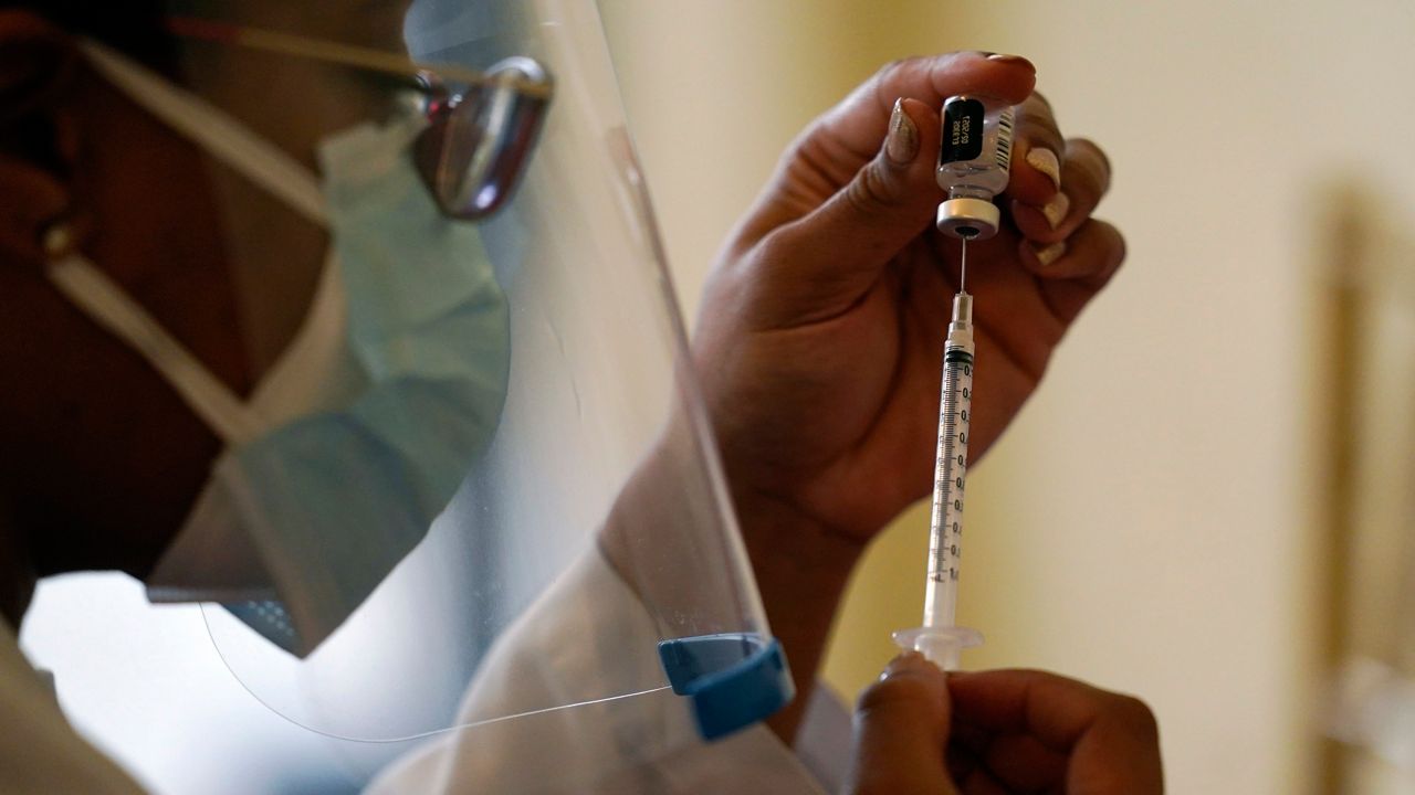 A medical professional puts a vaccine in a syringe